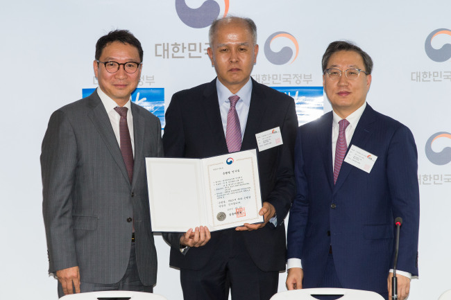 Lee Yong-woo (center) and Yun Ho-young (right), co-CEOs of KakaoBank of Korea, pose with Kim Hak-soo, director general of the banking and insurance bureau of the Financial Services Commission on Wednesday after receiving a banking license. (FSC)