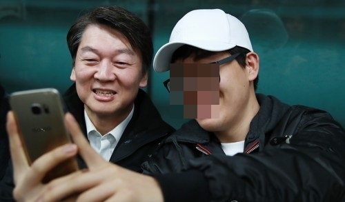 Ahn Cheol-soo (L), the presidential nominee of the centrist People's Party, takes a selfie with a passenger on the subway in Seoul on April 5, 2017. (Yonhap)