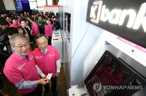 FSC Chairman Yim Jong-yong (left) and KT CEO Hwang Chang-gyu demonstrate operation of K bank services at the bank‘s launch ceremony held at the KT headquarters in Gwanghwamun on April 3. (Yonhap)