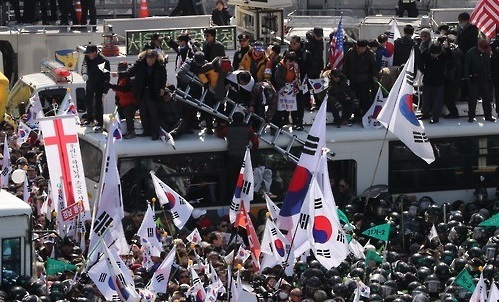 supporters of ousted President Park Geun-hye attempt to cross over the barricades of police buses during a protest held against the Constitutional Court's decision to remove her from office on the same day. (Yonhap)