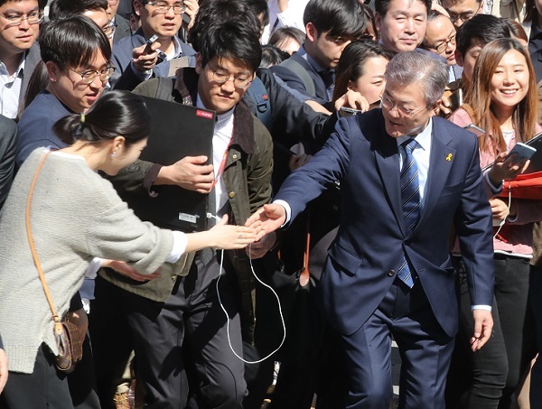Moon Jae-in (C), the presidential candidate of the liberal Democratic Party, shakes hands with a female supporter while visiting Gwanghwamun Square, the venue of weekly candlelight vigils in downtown Seoul that helped propel the recent ouster of former President Park Geun-hye, on April 10, 2017. (Yonhap)
