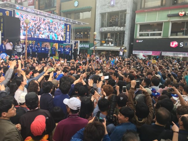 Citizens watch Moon Jae-in of the Democratic Party of Korea giving a speech on a makeshift stage truck in Uijeongbu, Gyeonggi Province, Monday. (Jo He-rim/The Korea Herald) 