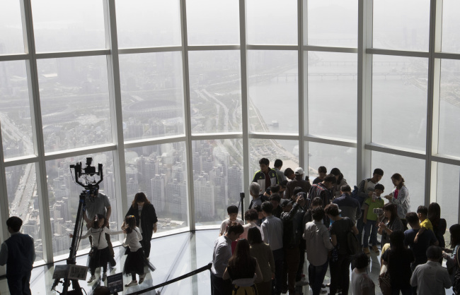 Visitors line up to take a look at the foggy skies of Seoul from the Lotte World Tower Seoul Sky, located in Songpa-gu on Saturday. (Yonhap)