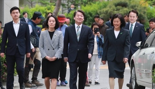 Ahn Cheol-soo, presidential candidate of the People's Party, walks toward a polling station in northeastern Seoul on May 9, 2017, flanked by his daughter (left) and wife. (Yonhap)