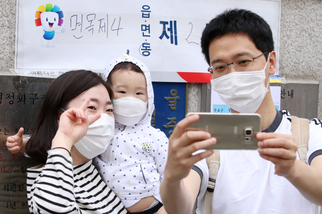 A family wearing masks poses for a photo after casting their votes for the presidential election in Myeonmok-dong, Seoul, Tuesday. Yonhap