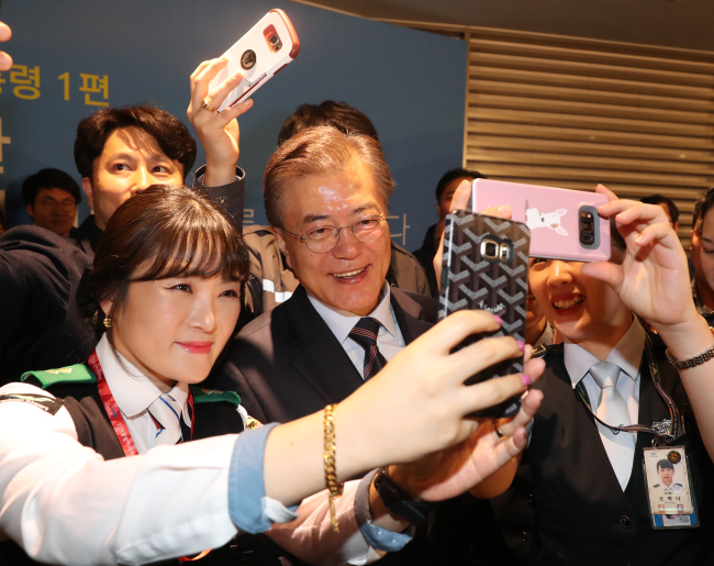 President Moon Jae-in poses for a selfie with employees of the Incheon International Airport Corp. on Friday, after making a pledge to promote the airport‘s temporary workers into regular employees. (Yonhap)