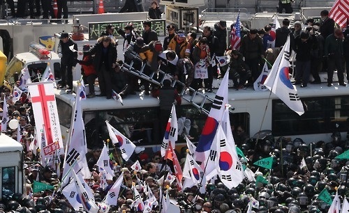 Supporters of ousted President Park Geun-hye attempt to cross over the barricades of police buses during a protest held against the Constitutional Court's decision to remove her from office on the same day. (Yonhap)