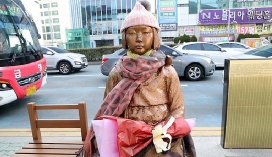 A statue of a girl symbolizing former Korean sex slaves for Japanese soldiers during World War II is seen wearing a scarf and a woolen hat in front of the Japanese Consulate in the southern South Korean port city of Busan on Jan. 7, 2017. (Yonhap)