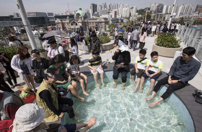 Visitors dip their feet in a mini pool at the newly opened park on Saturday. (Yonhap)
