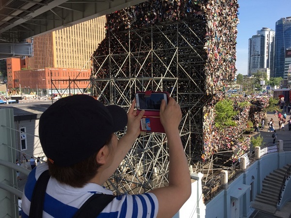 A partipant of the Seoul Metropolitan Government’s “Arts on Seoul’s street found by citizens” takes a photo of installation art Shoes Tree in Seoul Station on Saturday. (Kim Da-sol/The Korea Herald)