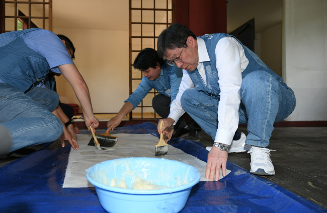 Posco Chairman Kwon Oh-joon (right) participates in a volunteer event repairing a historical landmark lecture hall in Sungkyunkwan University. (Posco)