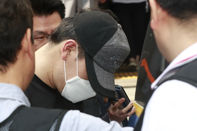 The suspect in a recent bomb blast at Yonsei University is surrounded by reporters as the police take him to a court on June 15, 2017. (Yonhap)