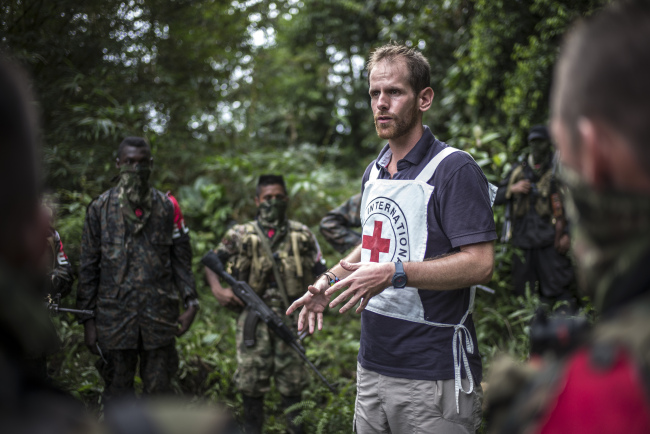 An ICRC operator speaks to members of the ELN armed guerilla group about the principles of international humanitarian law and obligations to protect civilian lives in a jungle in Colombia (The International Committee of the Red Cross)