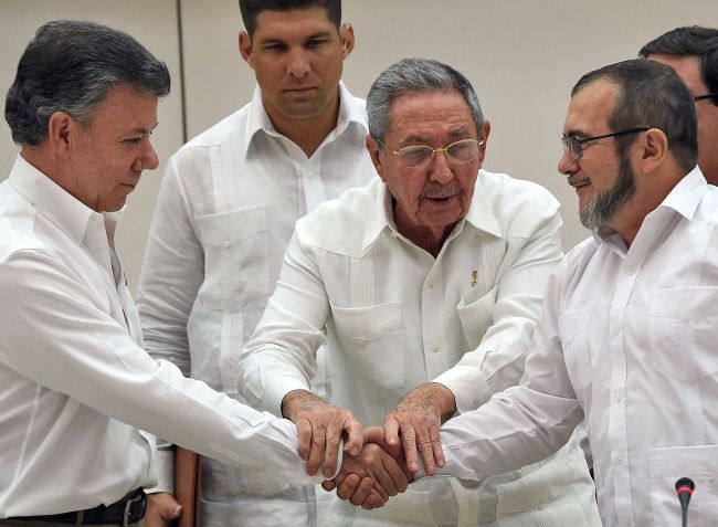 This file photo taken on September 23, 2015 shows Colombian President Juan Manuel Santos (left) and the head of the FARC guerrillas Timoleon Jimenez, aka Timochenko (right), shaking hands as Cuban President Raul Castro (center) holds their hands during a meeting in Havana. (Yonhap)