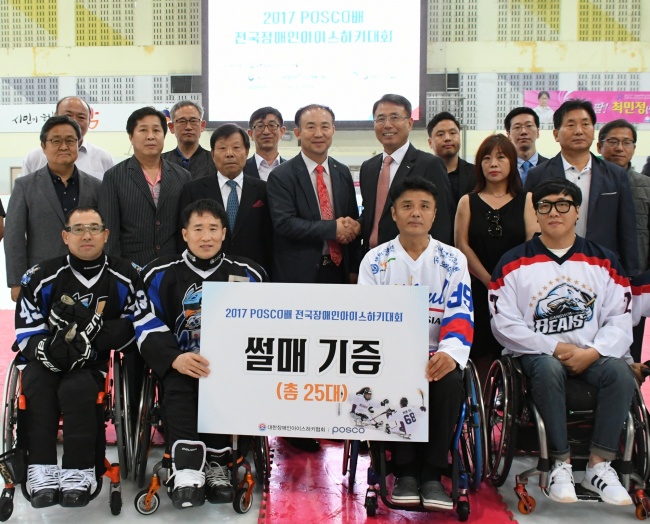 Posco‘s chief operating officer Oh In-hwan (sixth from right, second row) poses for a photo session after delivering custom-made sleds to be used by South Korea’s Paralympic ice-sledge hockey at a sports complex in Seongnam, Gyeonggi Province last week. (Posco)