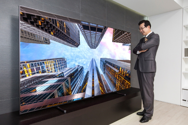 A consumer takes a look at an 88-inch QLED TV displayed at an outlet in Siheung, Gyeonggi Province. (Samsung Electronics)