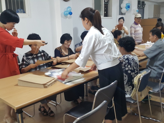 Senior North Korean defectors learn how to pack envelopes in plastic wrappings at a Korea Hana Foundation assistance center in Seoul. (Jung Min-kyung/The Korea Herald)