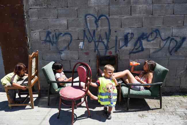 Roma children sit in front of their house in the Roma neighborhood in the town of Mitrovica on July 7. The Roma 