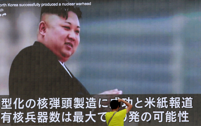 A man takes a photo of a TV news program in Tokyo, showing an image of North Korean leader Kim Jong Un Wednesday, Aug. 9, 2017. (AP-Yonhap)