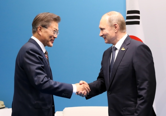 This file photo taken on July 7, 2017, shows South Korean President Moon Jae-in (L) shaking hands with Russian President Vladimir Putin in Germany. (Yonhap)