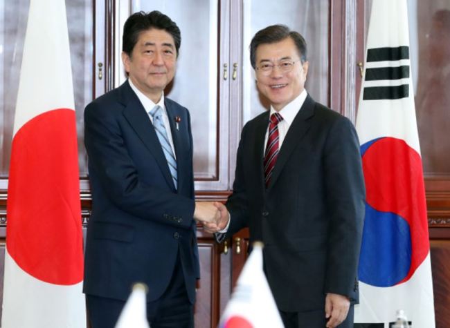 Japanese PM Shinzo Abe (left) and Korean President Moon Jae-in meet in Vladivostok. (Yonhap)