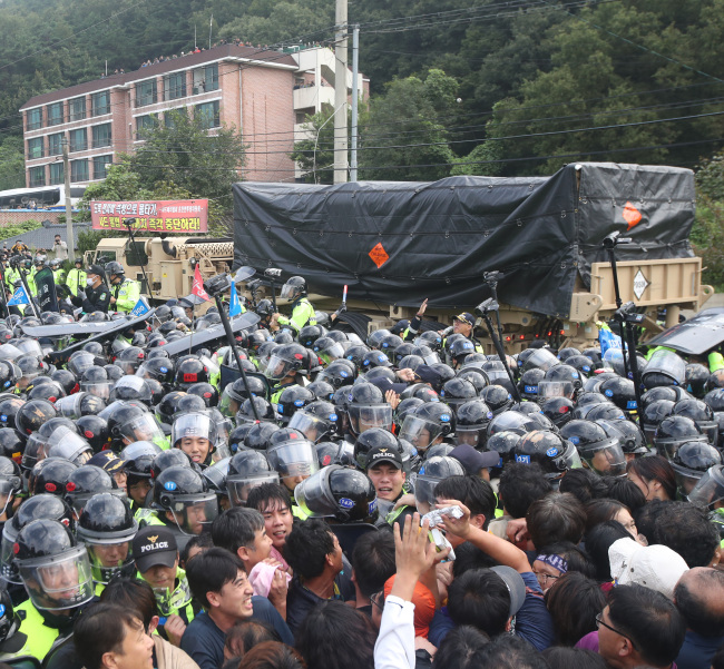 THAAD launchers move past protesters early morning on Thursday (Yonhap)