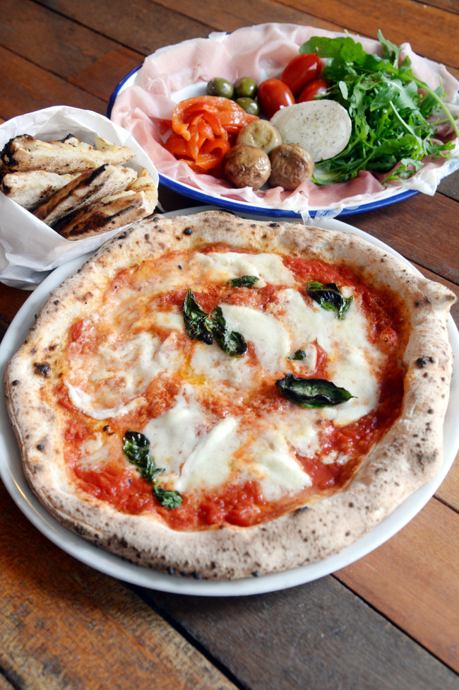 Darobe’s Margherita (front) couples tart-sweet San Marzano tomatoes with mozzarella and fresh basil; focaccia (left) -- smoky, nutty and chewy -- is also baked-to-order in the wood-fired oven. (Photo credit: Park Hyun-koo/The Korea Herald)