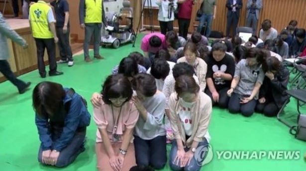 Parents of handicapped students kneel before residents of a Seoul neighborhood to call for support for the construction of a school for disabled children. (Yonhap)