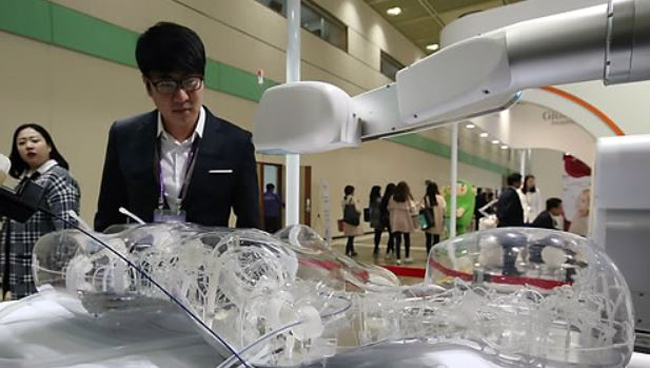 A spectator watches a robot demonstrating a surgical procedure during a Bio & Medical Korea exhibition in Seoul. (Yonhap)