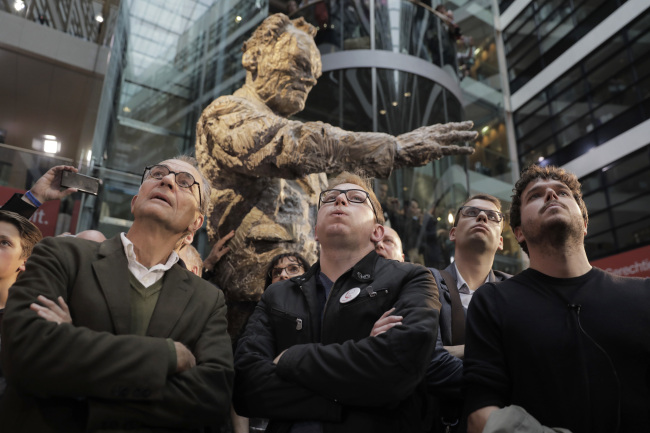 A statue of late chancellor Willy Brandt (1913-92) is seen in the background as people react to the first preliminary results at the headquarters of the Social Democratic party in Berlin, Germany, Sunday, Sept. 24, 2017, after the polling stations for the German parliament elections had been closed. (AP Photo/Gero Breloer)