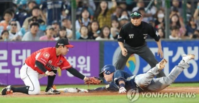 NC Dinos` Ji Seok-hun (R) slides into third base safely after a wild pitch by Lotte Giants` Park Si-young in the top of the 11th inning in Game 1 of the clubs` first round postseason series in the Korea Baseball Organization at Sajik Stadium in Busan on Oct. 8, 2017. The Dinos went on to take the game 9-2. (Yonhap)