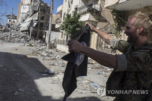 `IS 수도` 락까에서 IS기를 불태우는 SDF 대원(사진=AP-연합뉴스)