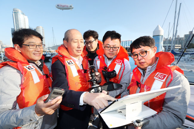 Oh Seong-mok (second from left) introduces the Marine Navi system and KT Skyship drone on a yacht in Suyeong Bay Yachting Center in Busan on Wednesday. (KT)