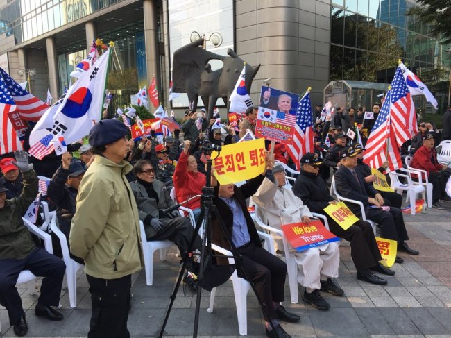 Participants wave national flags of South Korea and the US and hold placards saying 