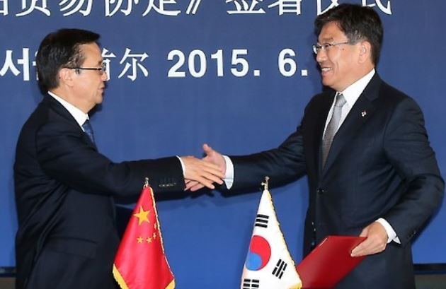 South Korean Trade Minister Yoon Sang-jick (R) and his Chinese counterpart Gao Hucheng shake hands after officially signing a free trade agreement (FTA) at a Seoul hotel on June 1, 2015. (Yonhap)