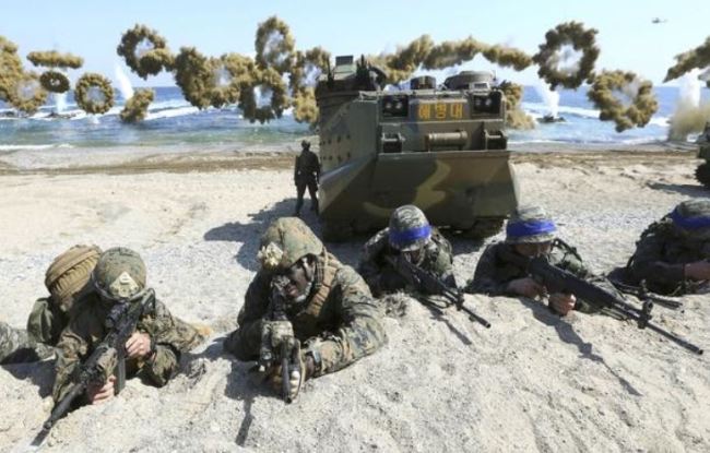 Marines of the US, left, and South Korea wearing blue headbands on their helmets, take positions after landing on a beach during a joint military exercise in March 2016 at Pohang, South Korea. (AP-Yonhap)