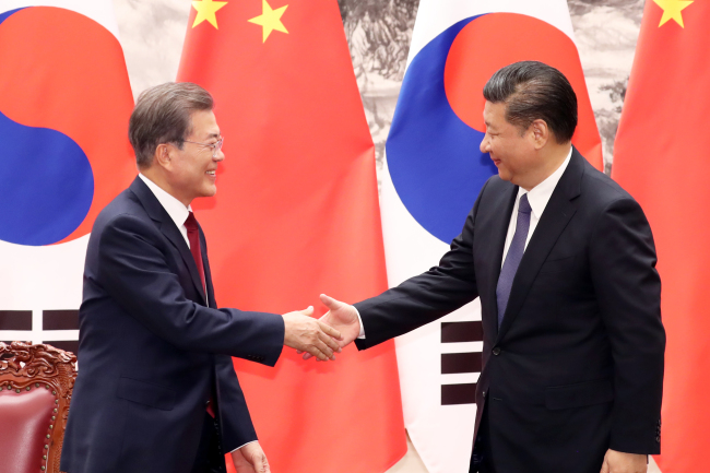 President Moon Jae-in shakes hands with Chinese President Xi Jinping during Thursday's summit in Beijing. (Yonhap)