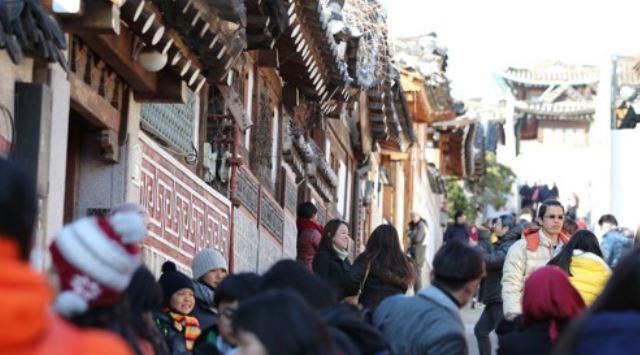 Foreign tourists bustle around in an alley of traditional Korean houses at Bukchon Village in Seoul despite the cold snap on Dec. 8, 2017. (Yonhap)