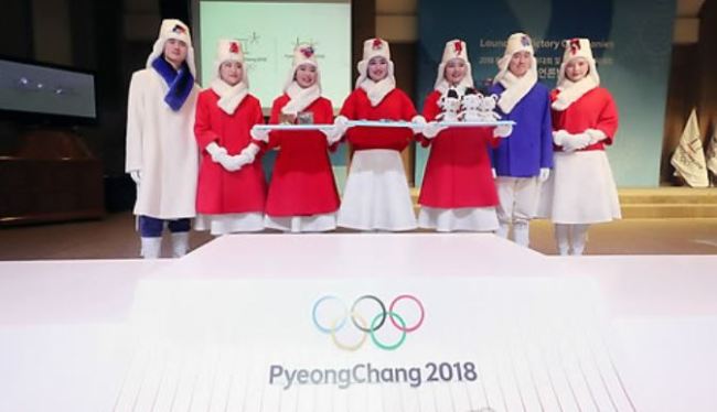 South Korean models wearing costumes for the victory ceremonies at the PyeongChang Winter Olympic and Paralympic Games pose for a photo behind the Olympic podium at an event in Seoul on Dec. 27, 2017. (Yonhap)