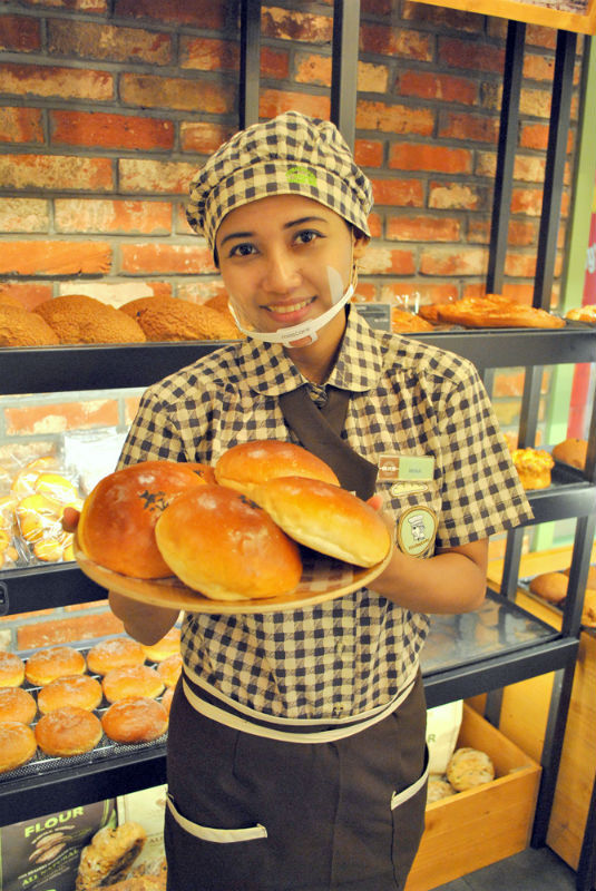 An employee holds up bread at a Tous Les Jours branch in Indonesia (CJ Foodville)