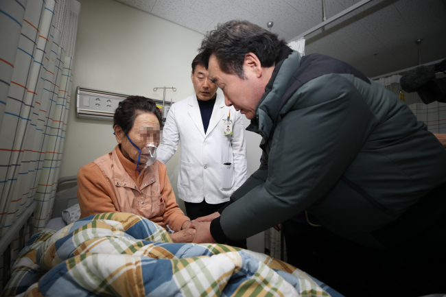Prime Minister Lee Nak-yon holds the hands of an elderly woman injured in a hospital fire in South Korea`s southeastern city of Miryang on Jan. 26. (Yonhap)