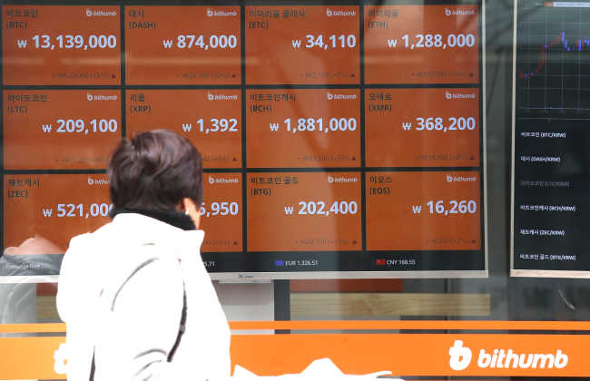 A citizen on Sunday scans cryptocurrency prices on the display board of Bithumb, one of South Korea's largest cryptocurrency operators. (Yonhap)