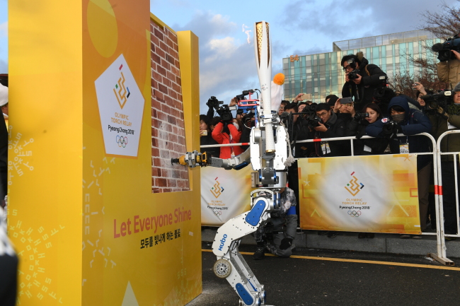 Hubo the humanoid robot breaks through a brick wall as he proceeds to pass the Olympic torch to the next human in line (Yonhap)
