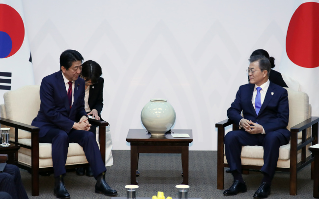 South Korean President Moon Jae-in (R) and Japanese Prime Minister Shinzo Abe hold a bilateral summit in South Korea`s eastern city of Yongpyeong, located 200 kilometers from Seoul, on Friday. (Yonhap)