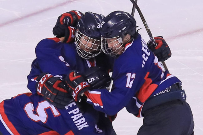 Randi Heesoo Griffin (center) celebrates with teammates after scoring Korea’s first-ever Olympic goal in hockey, during a match against Japan on Wednesday. Yonhap