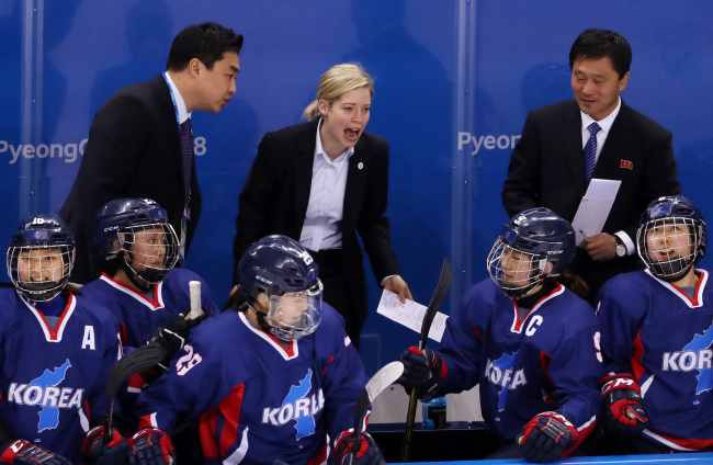 Sarah Murray, the Canadian coach of the unified Korean women’s hockey team, stands and cheers after her team scored Korea’s first-ever hockey goal in any Olympics. Yonhap