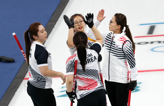 South Korea’s Olympics women’s curling team shares a high-five after beating Sweden 7-6 in the round robin match held at the Gangneung Curling Centre on Monday. The Korean team now has a track record of five wins and one loss. (Yonhap)