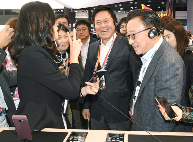 SK Telecom CEO Park Jung-ho (center) and DJ Koh (right), president and Head of IT & Mobile Communications Division, Samsung Electronics, look at Samsung`s Galaxy S9 at the tech firm`s booth at Mobile World Congress in Barcelona, Spain, Monday. (SK Telecom)