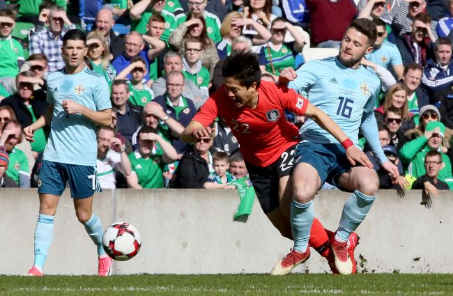 South Korea`s midfielder Kwon Chang-hoon (C) is tackled by Northern Ireland`s midfielder Oliver Norwood during the international friendly football match between Northern Ireland and South Korea at at Windsor Park in Belfast on March 24, 2018. (AFP-Yonhap)