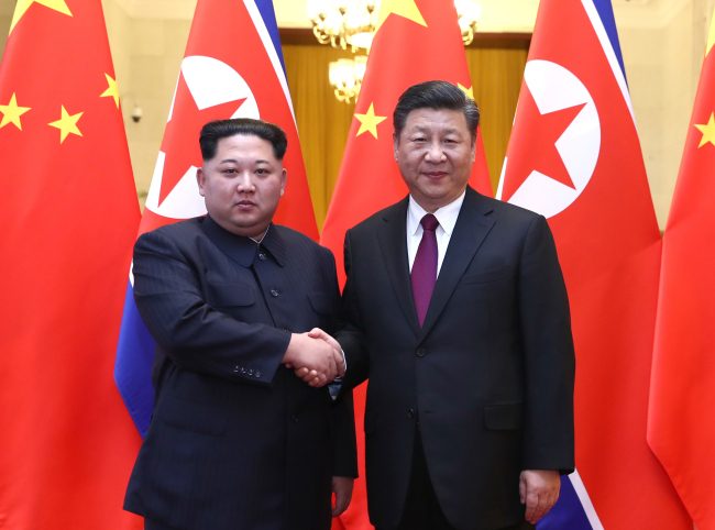 North Korean leader Kim Jong-un, left, shakes hands with Chinese President Xi Jinping on March 28. (Yonhap)